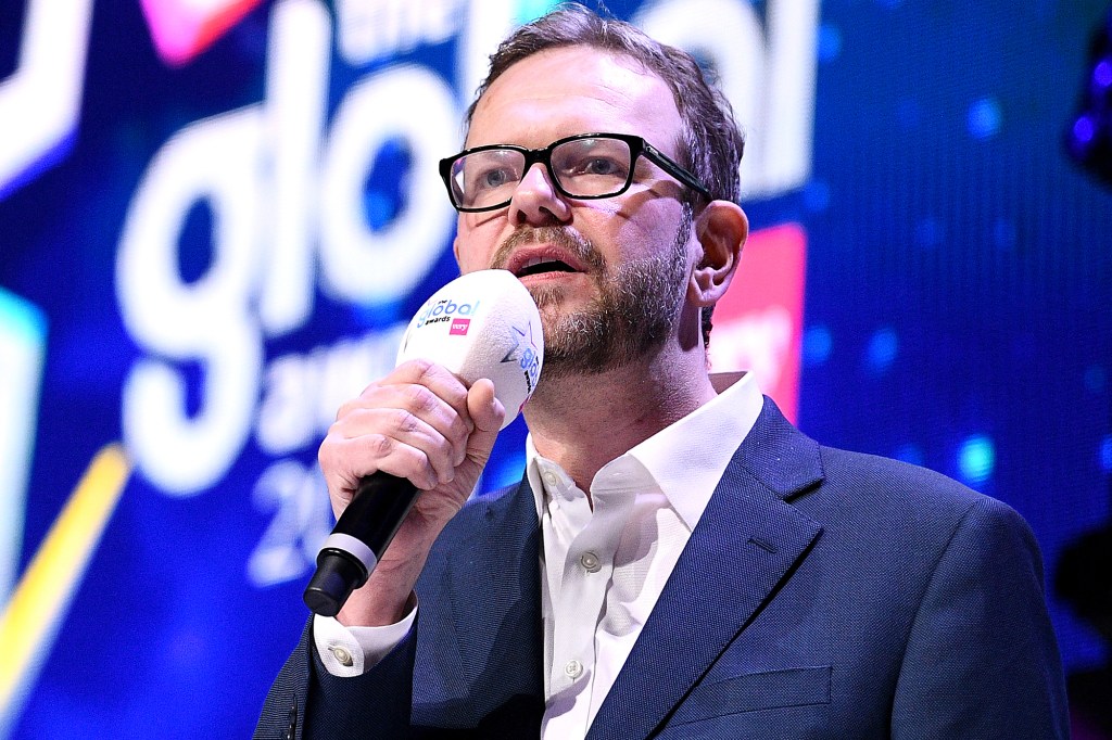 Presenter James O'Brien in suit holding a microphone on stage at the Global Awards 2020 at Eventim Apollo Hammersmith, London